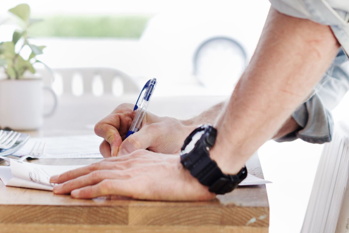 Persona firmando un documento sobre un escritorio