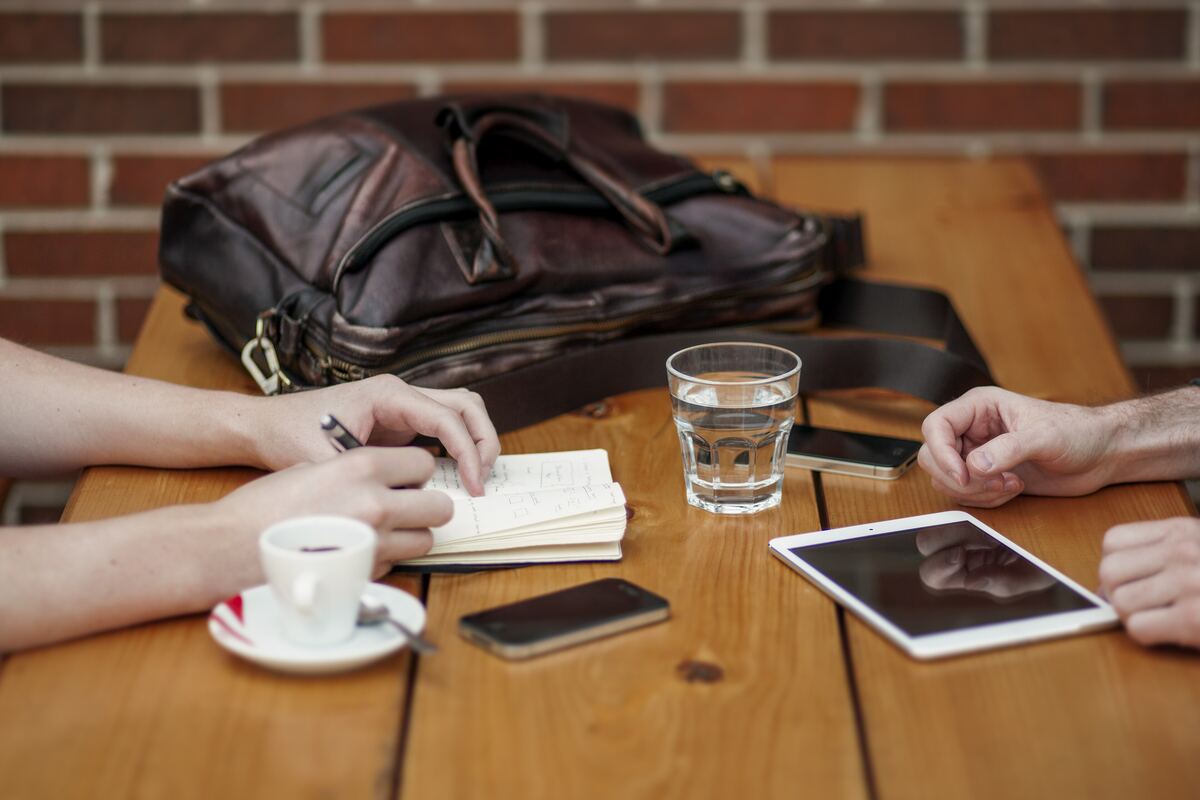 Dos personas en una reunión de trabajo revisando notas y una tableta