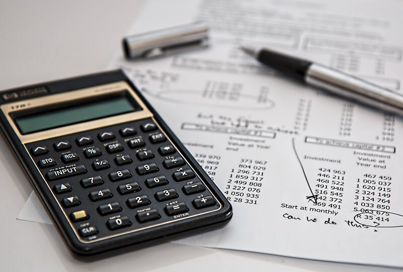 Calculadora y pluma sobre hojas con cálculos de pagos